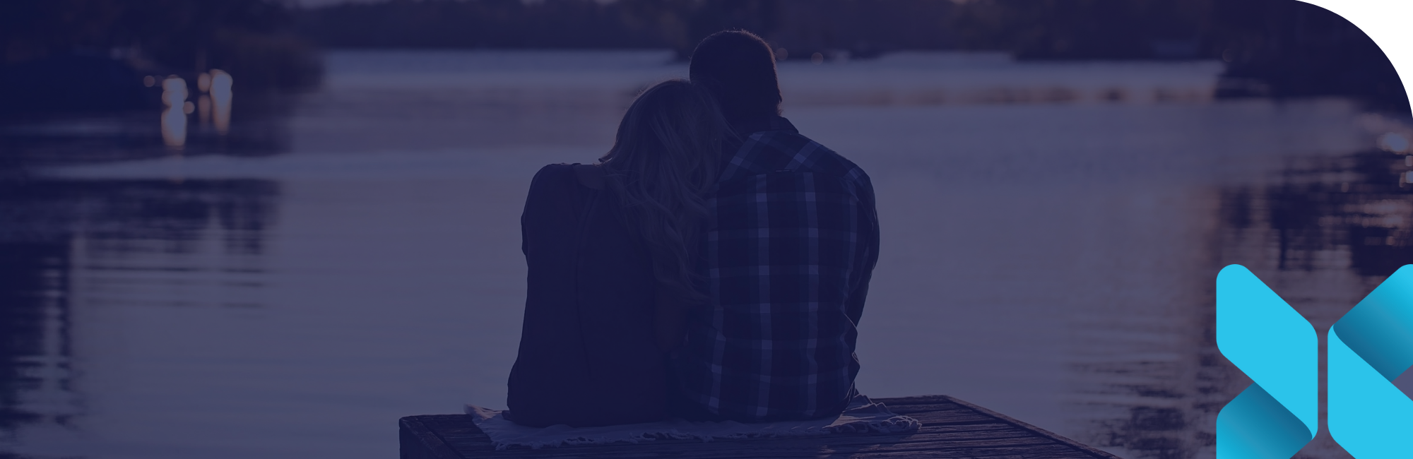 couple sitting on the end of a dock looking out at a lake