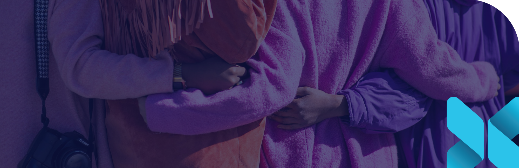 back of four women standing with their arms wrapped around each other in unity